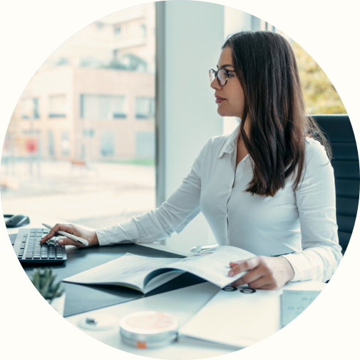 woman working on desktop and reviewing paper report